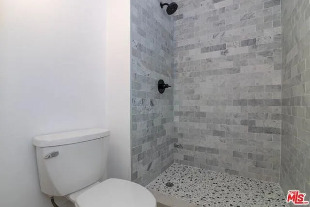 a white toilet sitting next to a shower