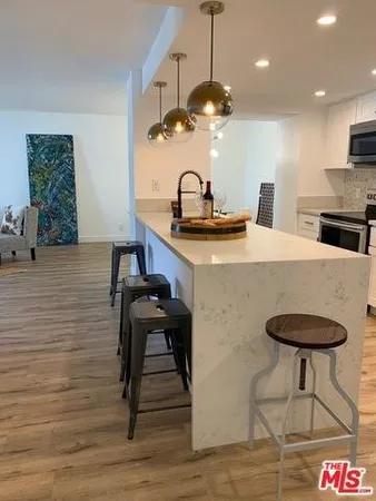 a kitchen with stainless steel appliances granite countertop a sink a stove and a wooden floor