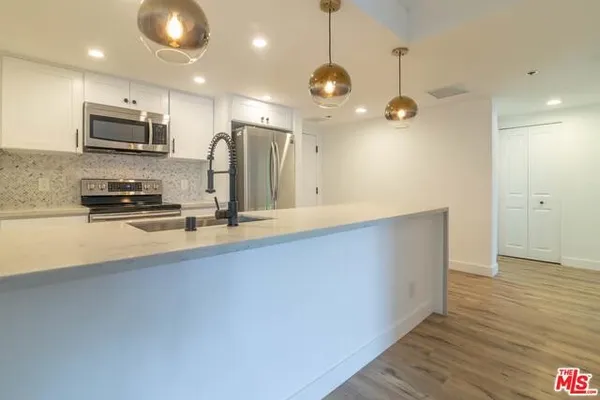 a large kitchen with stainless steel appliances a large counter top space cabinets and wooden floor