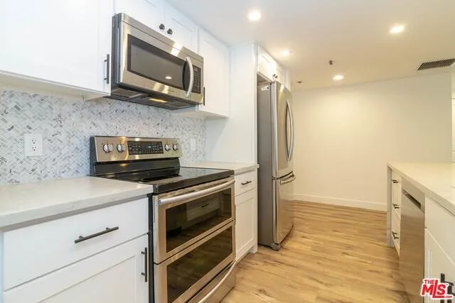 a kitchen with stainless steel appliances granite countertop a stove microwave and cabinets