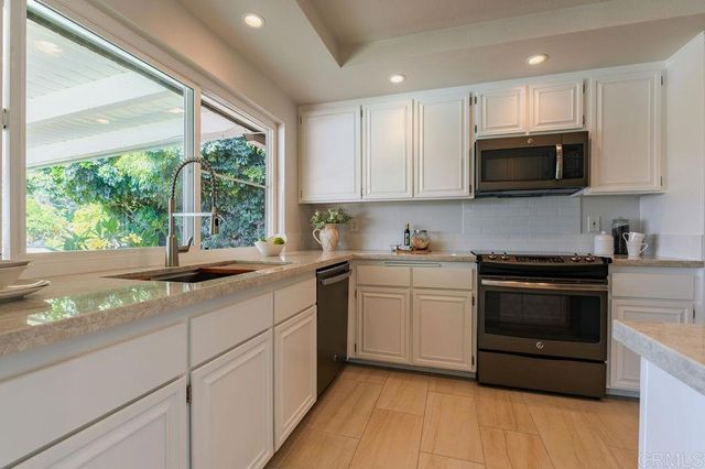 a kitchen with stainless steel appliances granite countertop a stove a sink and a microwave