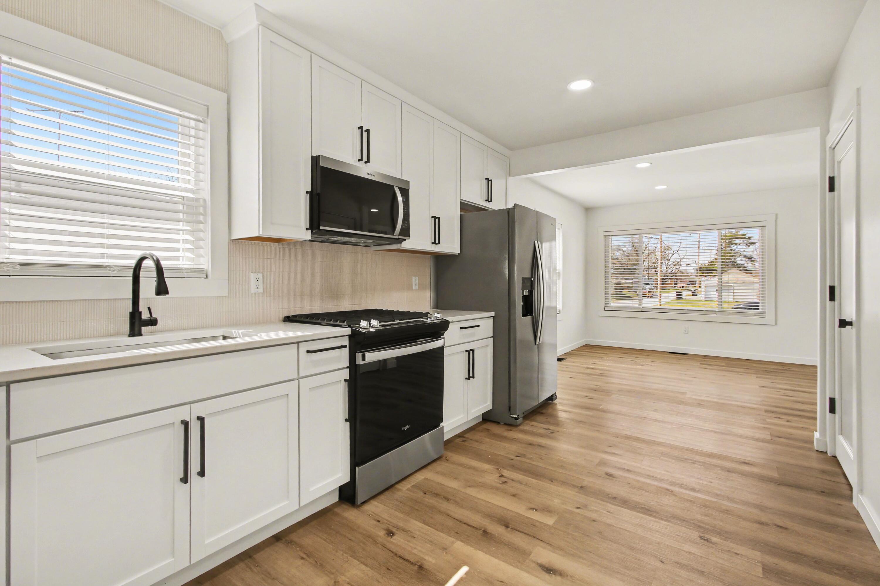 3517 Buchanan Street Gary, IN 46408 - Photo 5 of 18 a kitchen with stainless steel appliances a stove top oven a sink a refrigerator white cabinets and wooden floor