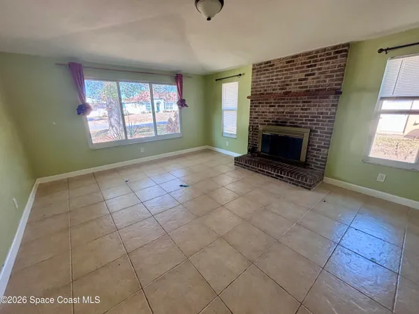 an empty room with windows and fireplace