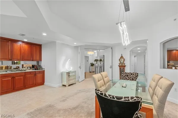 a living room with furniture a chandelier and kitchen view
