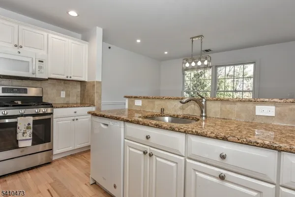 a kitchen with granite countertop white cabinets and white stainless steel appliances
