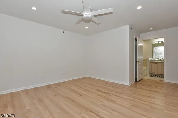 an empty room with wooden floor and a kitchen space