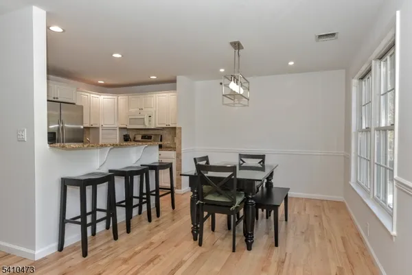 a kitchen with kitchen island a dining table chairs stainless steel appliances and cabinets