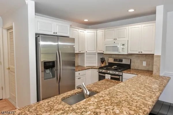 a kitchen with stainless steel appliances kitchen island granite countertop a refrigerator and a stove top oven