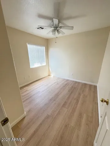 an empty room with wooden floor fan and windows