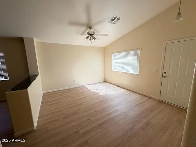 a view of an empty room with wooden floor and a window