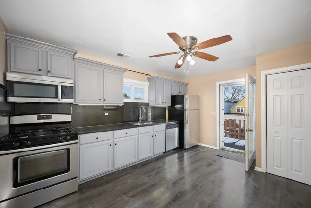 a kitchen with granite countertop a refrigerator a sink a stove and white cabinets