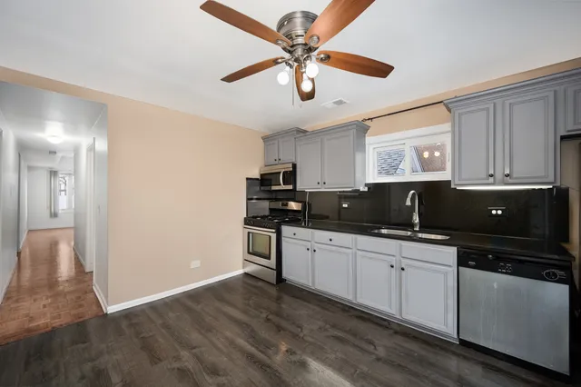 a kitchen with stainless steel appliances granite countertop a sink cabinets and wooden floor