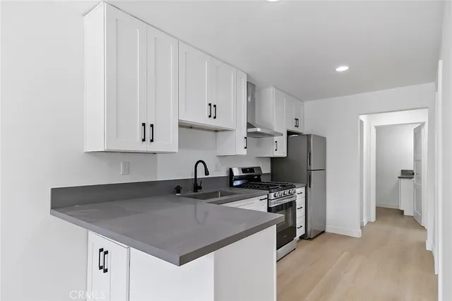 a kitchen with stainless steel appliances a sink a stove a refrigerator and cabinets