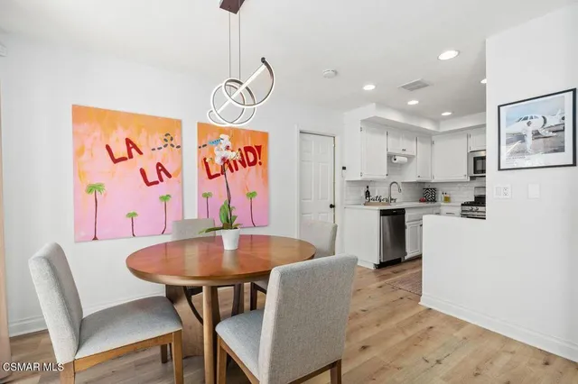 a kitchen with stainless steel appliances granite countertop a dining table chairs and a refrigerator