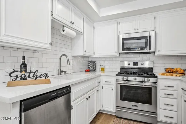 a kitchen with stainless steel appliances white cabinets and a stove a sink
