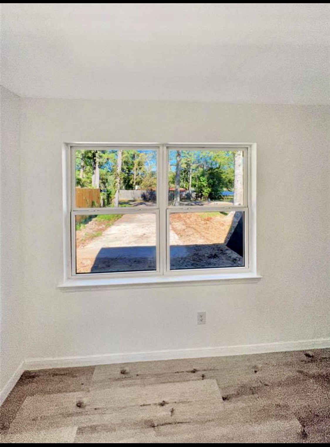 408 Commanche Road Conroe, TX 77316 - Photo 11 of 25 Bright and airy room with a large window offering serene views of the outdoors, complemented by soft carpeting and neutral wall tones.