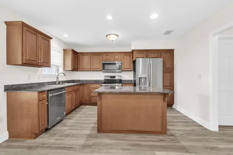 a kitchen with stainless steel appliances granite countertop a stove a sink dishwasher a refrigerator and a microwave oven with wooden floor