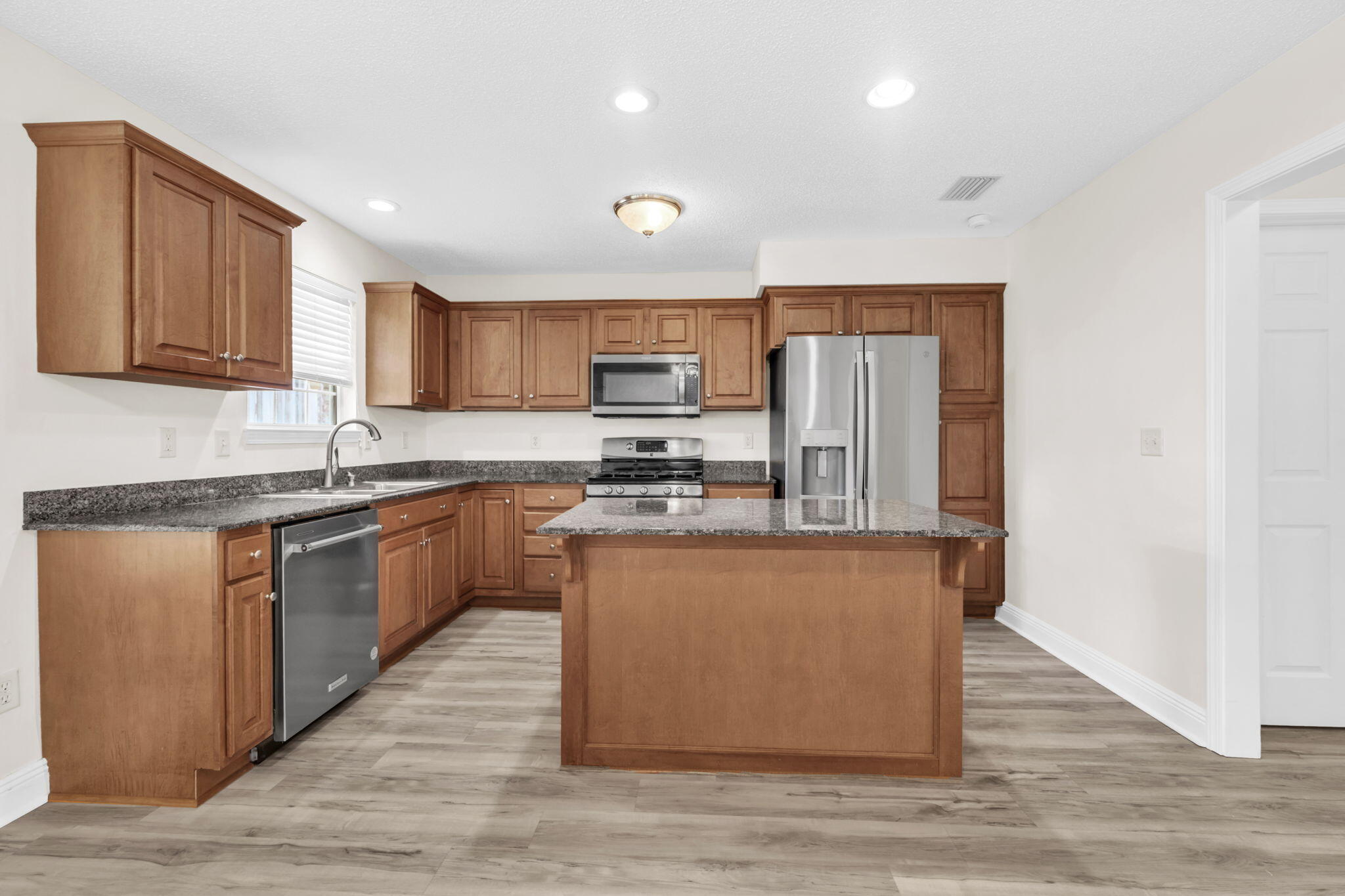 202 Gracie Lane Niceville, FL 32578 - Photo 21 of 47 a kitchen with stainless steel appliances granite countertop a stove a sink dishwasher a refrigerator and a microwave oven with wooden floor