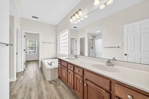 a spacious bathroom with a granite countertop sink a large mirror and a bathtub