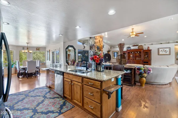 a kitchen with stainless steel appliances kitchen island granite countertop a stove a sink a dining table and chairs with wooden floor