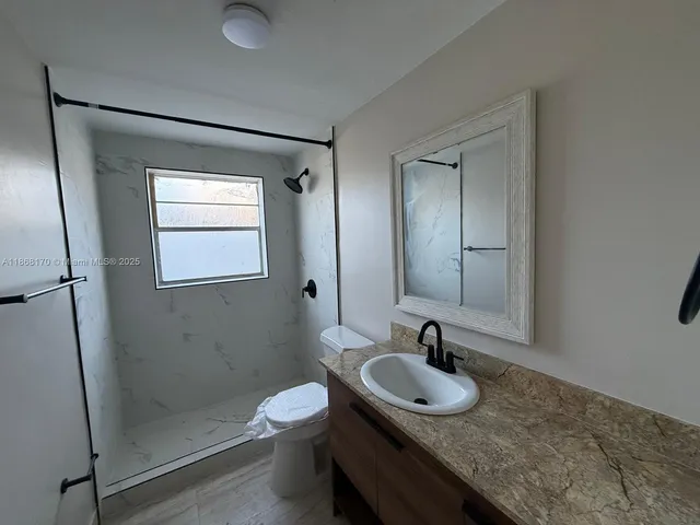 a bathroom with a granite countertop sink a toilet and a mirror