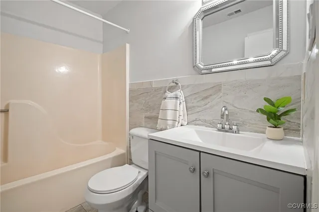a bathroom with a granite countertop sink a toilet a mirror a vanity and shower