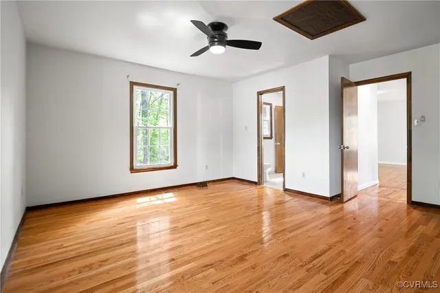 an empty room with wooden floor chandelier fan and windows