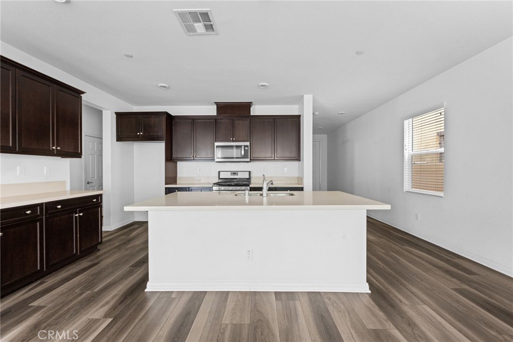 893 Harvest Avenue Upland, CA 91786 - Photo 6 of 40 a large white kitchen with stainless steel appliances a large counter top a stove a microwave a sink and cabinets