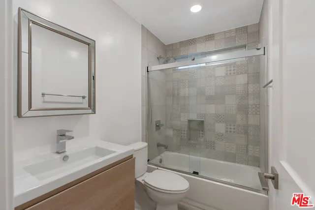 a bathroom with a bathtub shower sink vanity and toilet