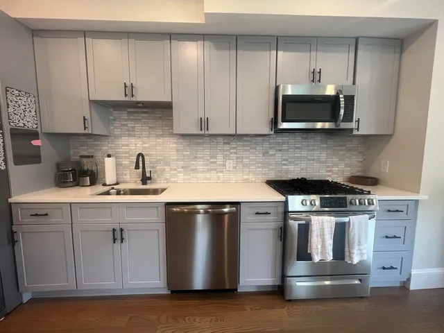 a kitchen with stainless steel appliances granite countertop a stove a sink and a microwave