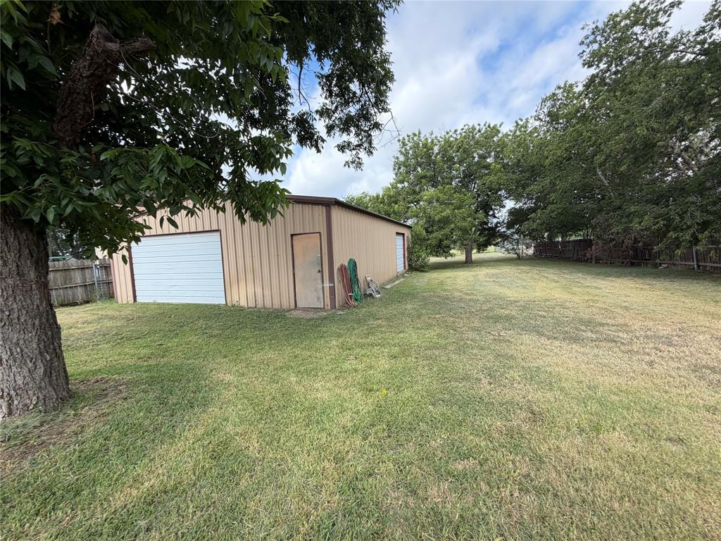 267 North Katy Road Elm Mott, TX 76640 - Photo 1 of 21 Detached metal outbuilding featuring a roll-up garage door and a side entry door