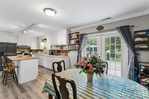 a kitchen with granite countertop a stove a sink dishwasher a dining table and chairs with wooden floor