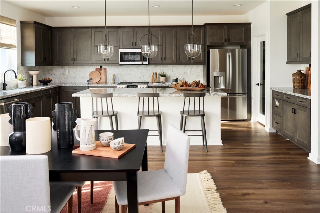 11531 Jack Street Beaumont, CA 92223 - Photo 5 of 16 a kitchen with stainless steel appliances kitchen island granite countertop a refrigerator a stove a sink a dining table and chairs with wooden floor