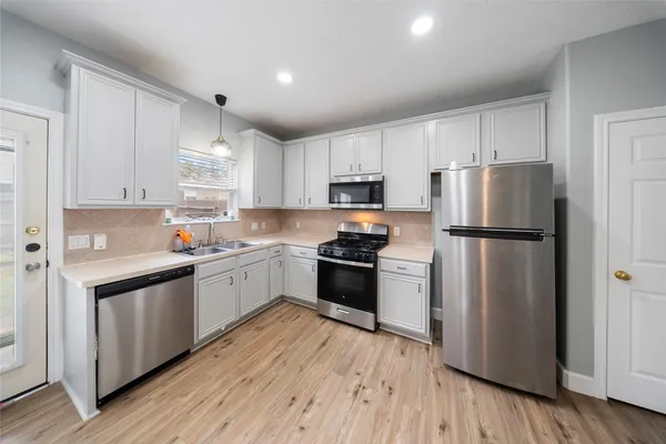 a kitchen with a refrigerator a stove top oven and white cabinets