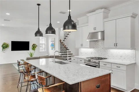 a kitchen with stainless steel appliances granite countertop a stove a sink a microwave a dining table and chairs with wooden floor