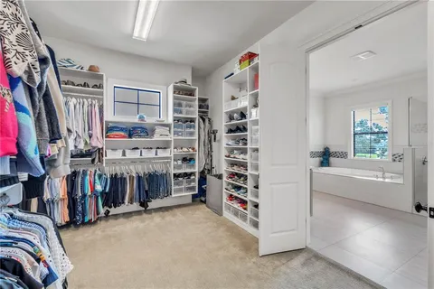 a view of walk in closet with clothes and shoes
