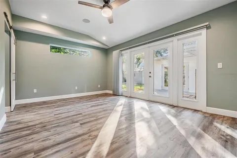 an empty room with wooden floor closet and windows