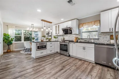 a kitchen with a white cabinets a sink a stove a refrigerator and white appliances