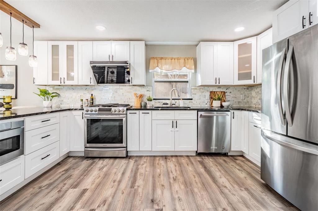 3216 West Fielder Street Tampa, FL 33611 - Photo 7 of 34 a kitchen with a white cabinets a sink a stove a refrigerator and white appliances
