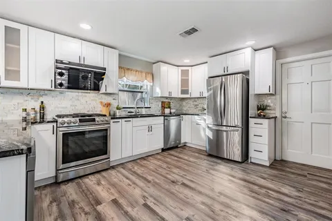 a kitchen with white cabinets and stainless steel appliances