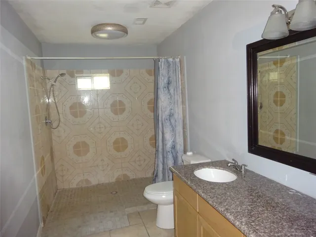 a bathroom with a granite countertop sink toilet and shower