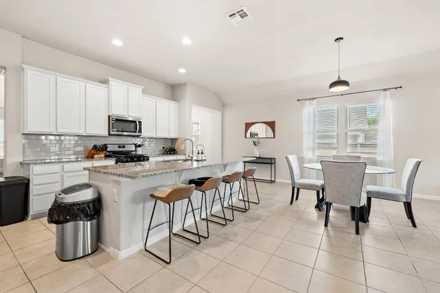 a kitchen with stainless steel appliances granite countertop a stove a sink a dining table and chairs