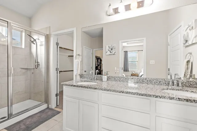 a bathroom with a granite countertop sink two mirror and shower