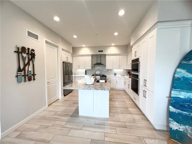 a large kitchen with kitchen island a stove a refrigerator a sink and a living room view