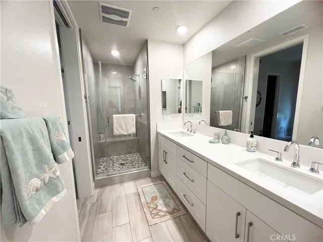 a bathroom with a double vanity sink and mirror with shower