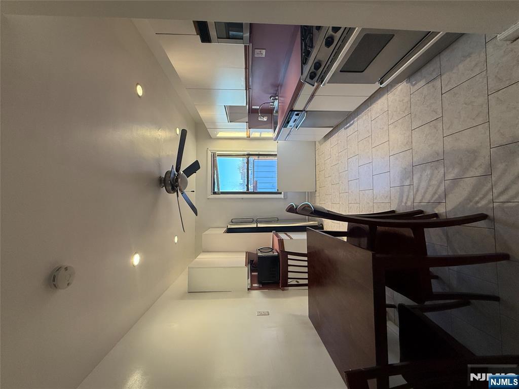 a kitchen with stainless steel appliances granite countertop a stove top oven a sink dishwasher a dining table and chairs with wooden floor