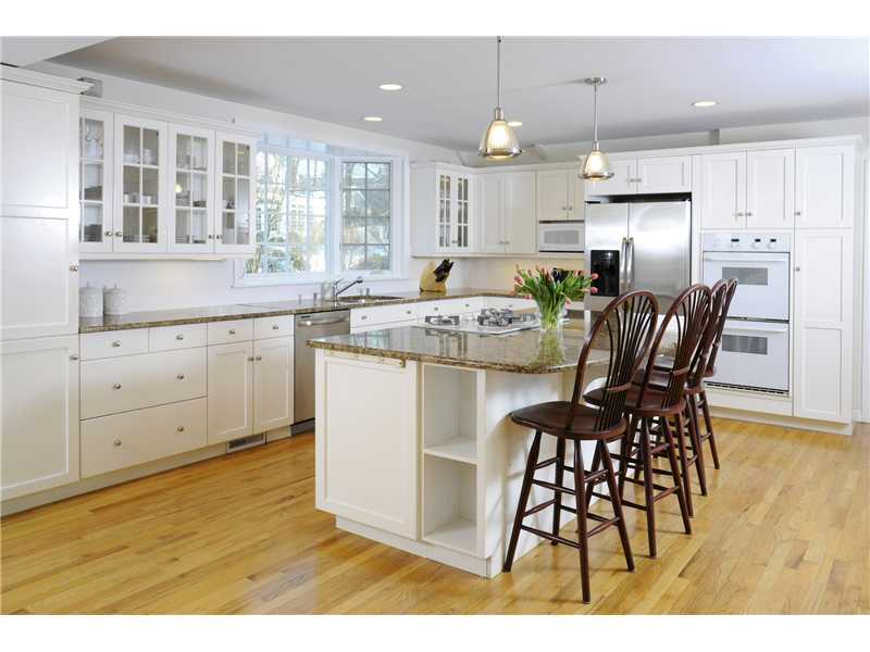 Undisclosed Address Riverside, CT 06878 - Photo 6 of 19 a kitchen with stainless steel appliances granite countertop a table chairs wooden floors a large window and white cabinets