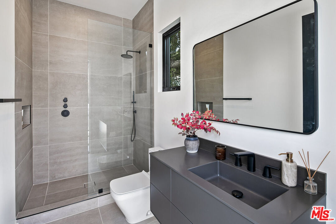 211 Veteran Avenue Los Angeles, CA 90024 - Photo 38 of 51 a bathroom with a granite countertop sink a toilet and shower