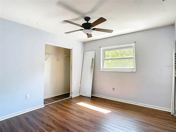an empty room with wooden floor ceiling fan and windows