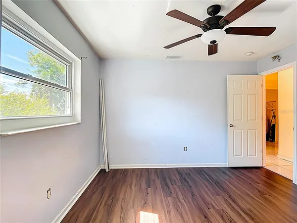 an empty room with windows and fan